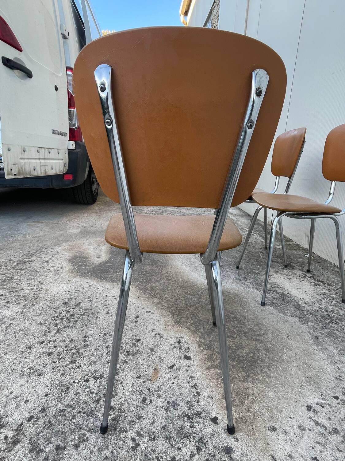 3 chairs and a vintage stool in faux leather and tubular design.