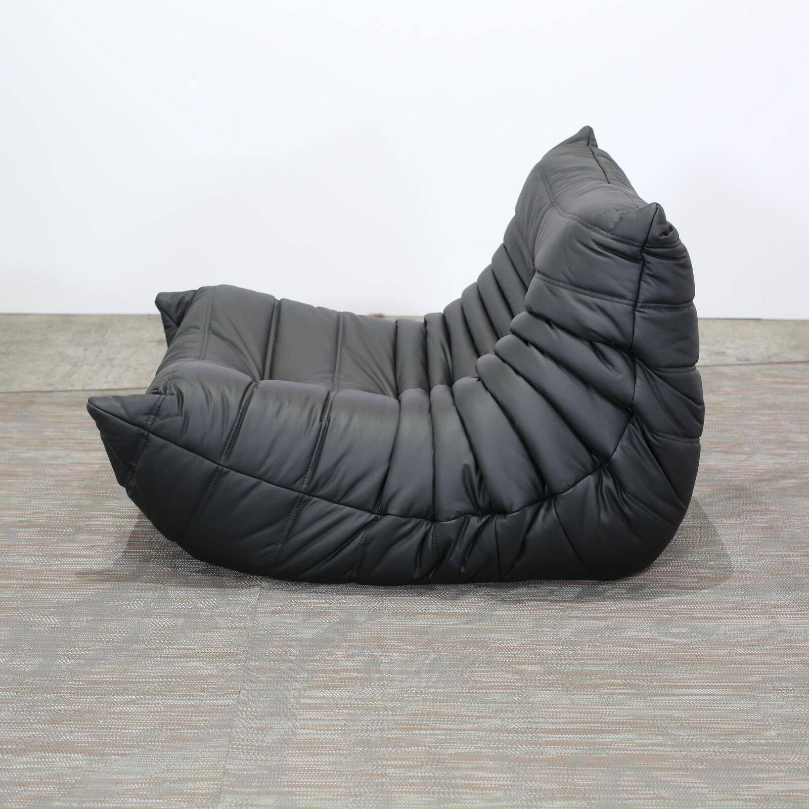 Togo armchair and footrest in black leather by Ligne Roset, designed by Michel Ducaroy.