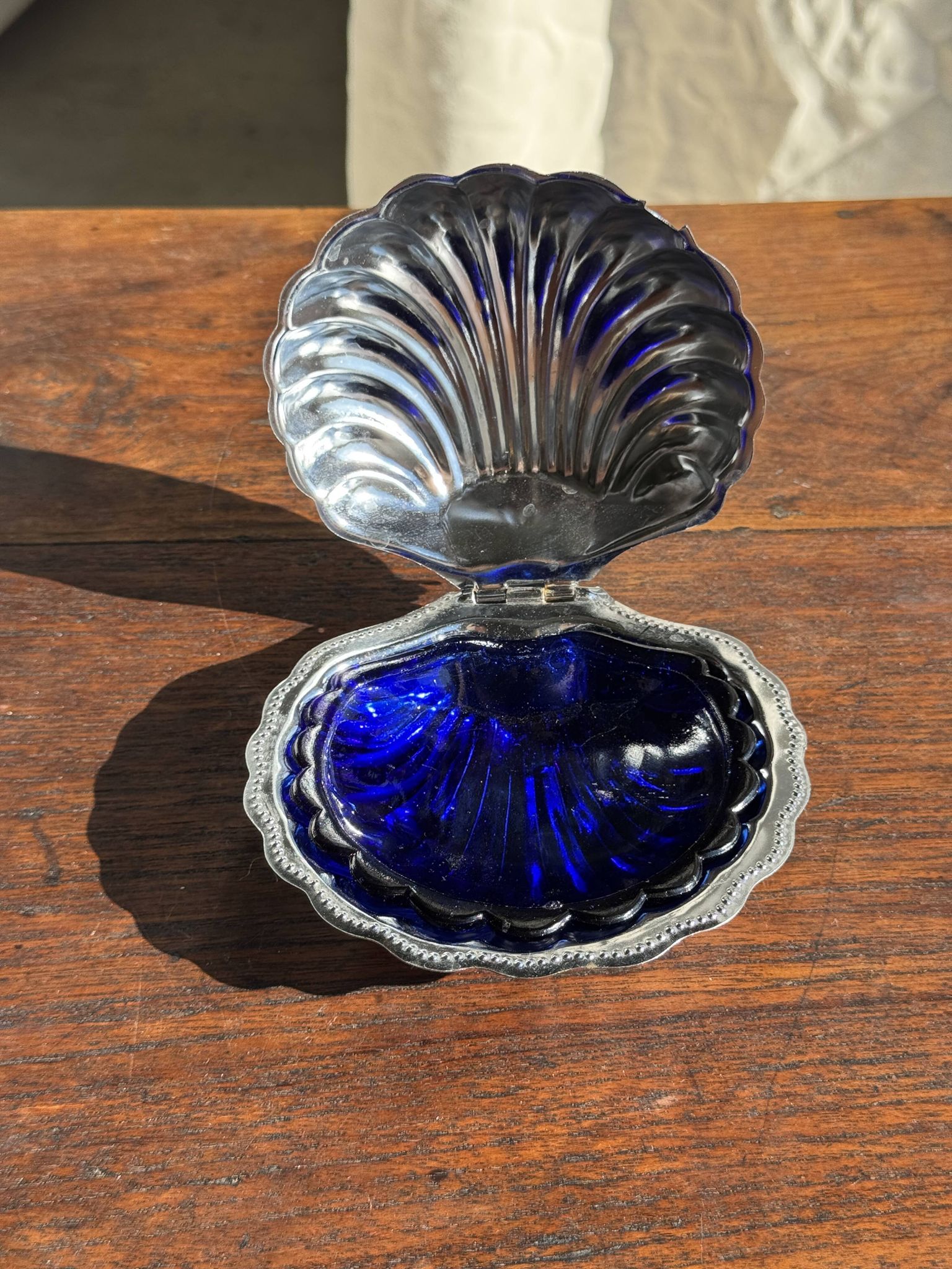 Vintage silver-plated shell butter dish with blue bowl.