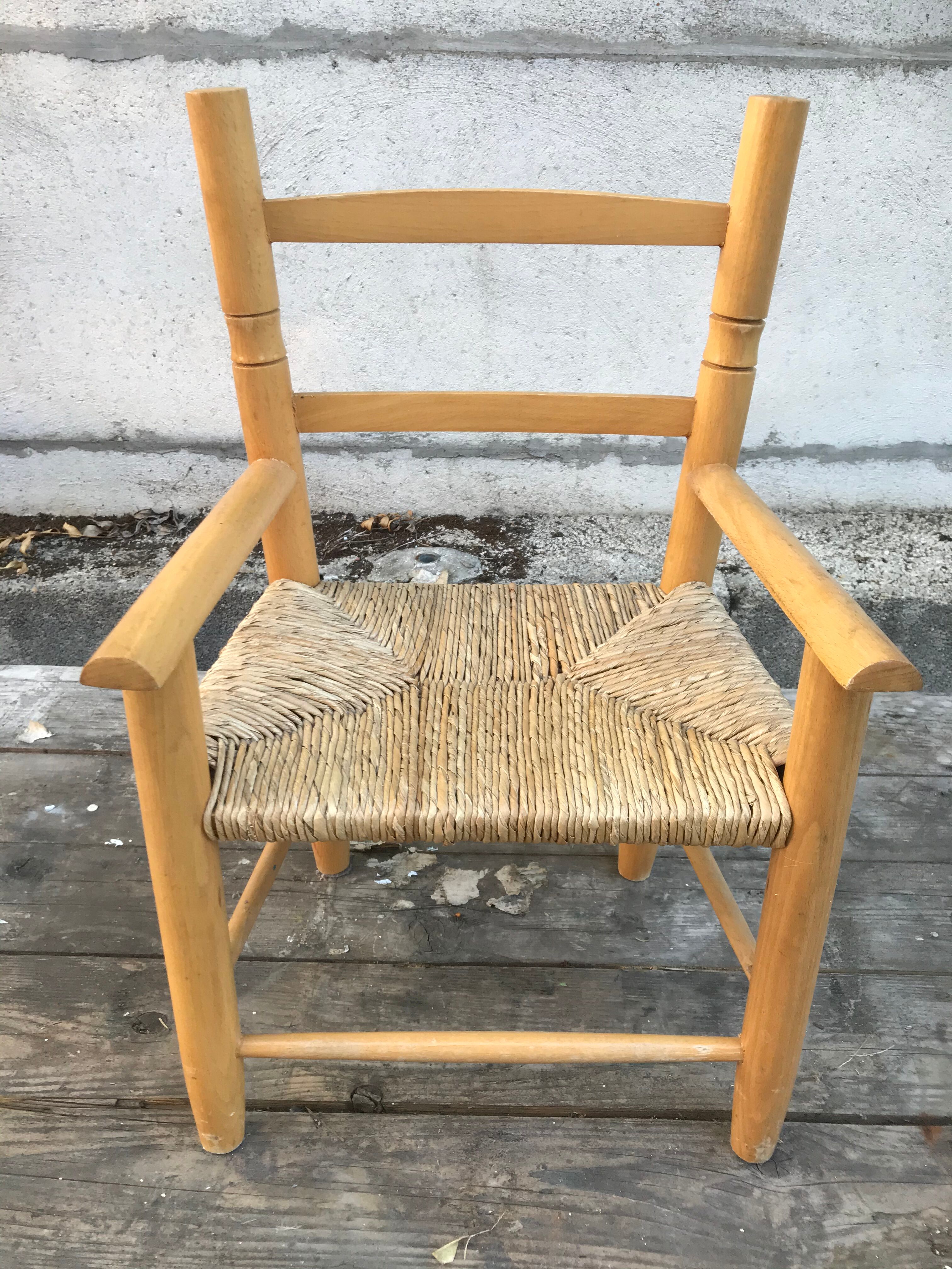 Old wooden children's armchair and vintage woven straw seat