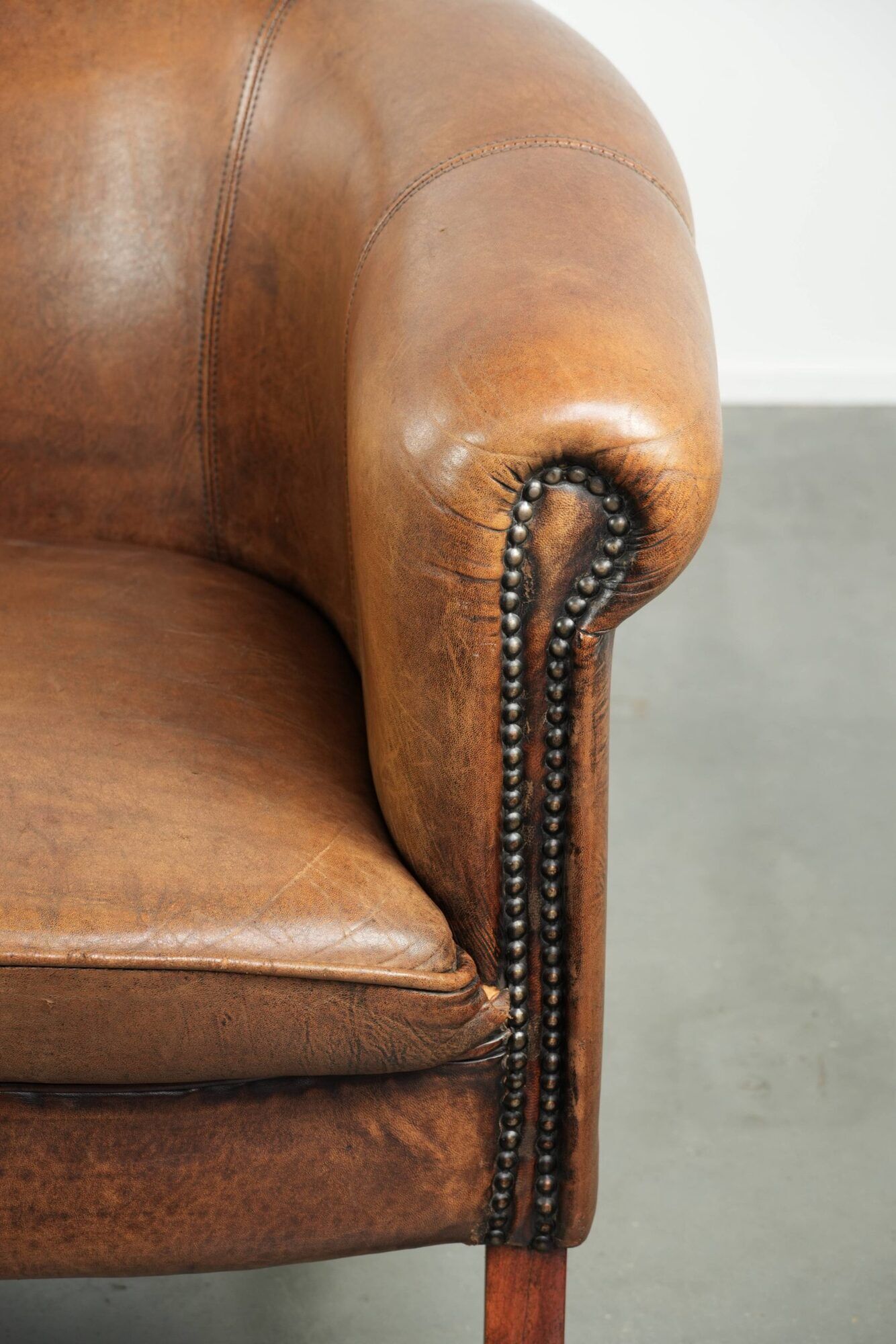Sheepskin club armchair in a brown colour finished with decorative nails