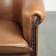 Sheepskin club armchair in a brown colour finished with decorative nails