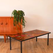 Ceramic and black iron coffee table, attributed to the Roche-Bobois brand, with a black metal base and structure, rectangular ceramic top from Vallauris with colourful patterns in ochre and orange, design from the 1970s.