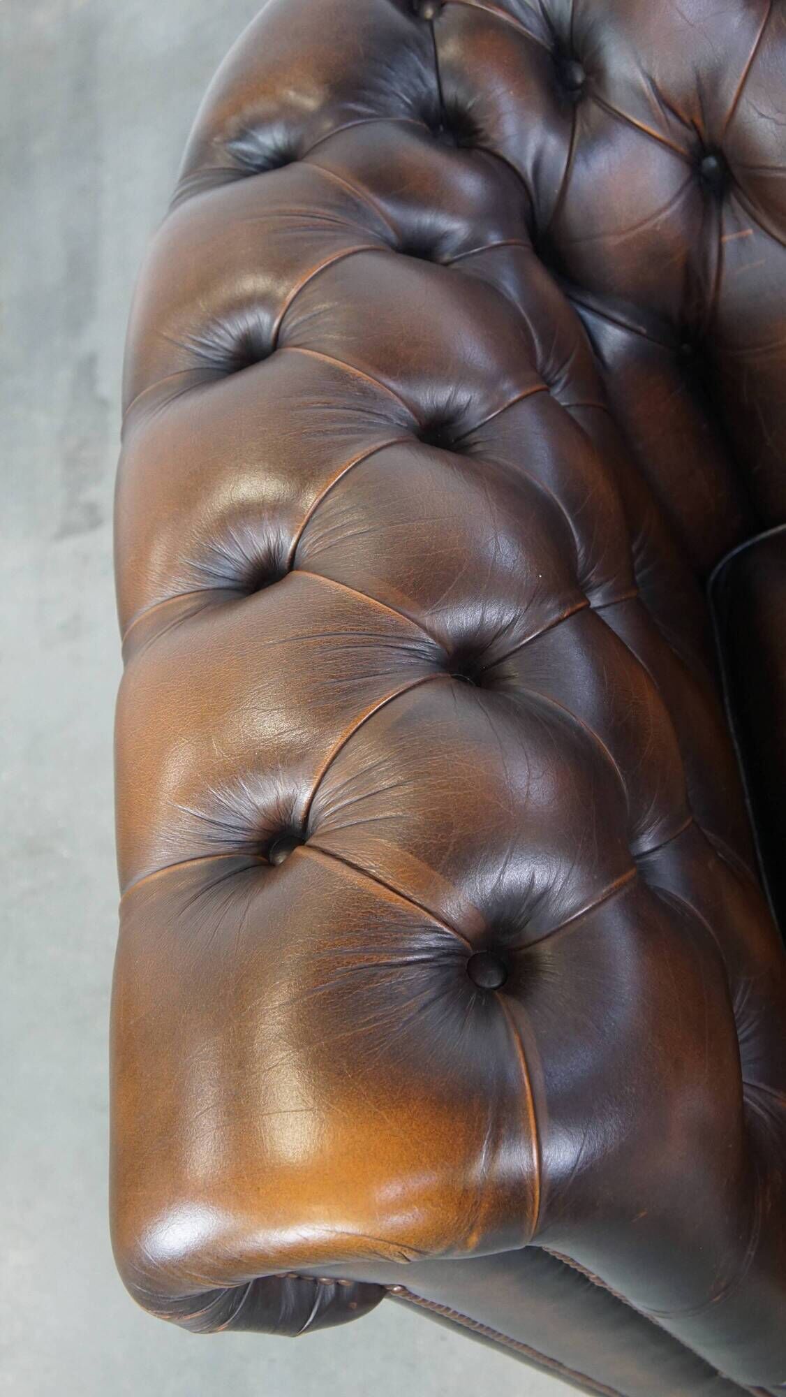 Cowhide English Chesterfield armchair with ball legs and timeless finish
