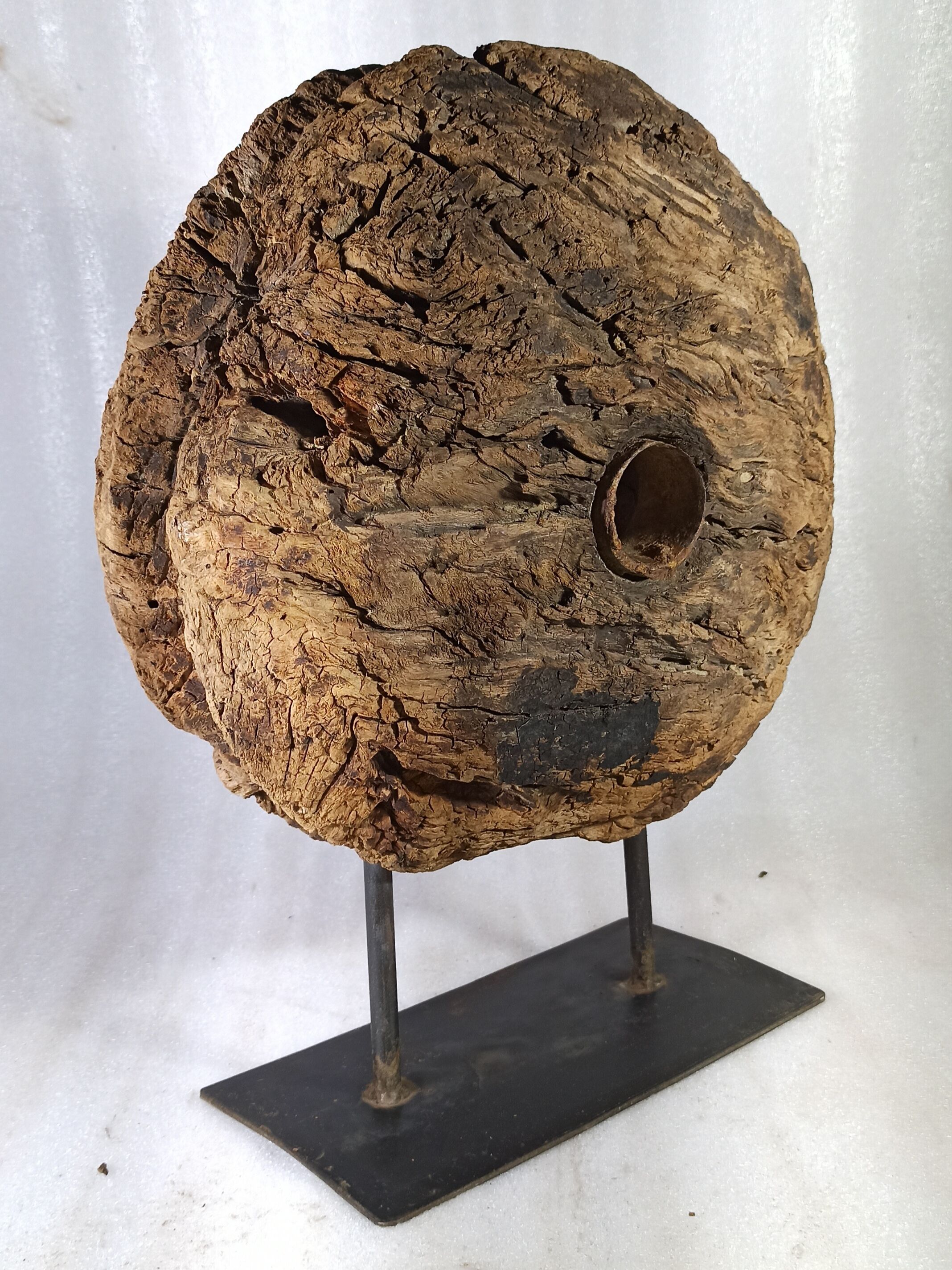 Old wooden pulley wheel on foot