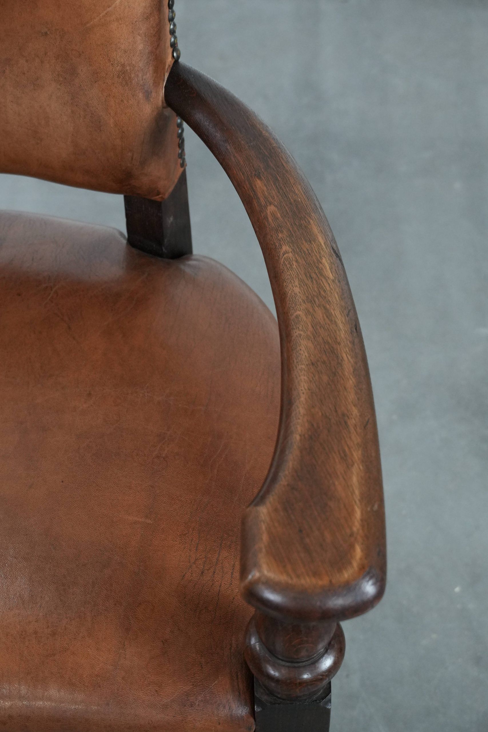 Elegant antique sheepskin leather desk chair with a heavy wooden frame