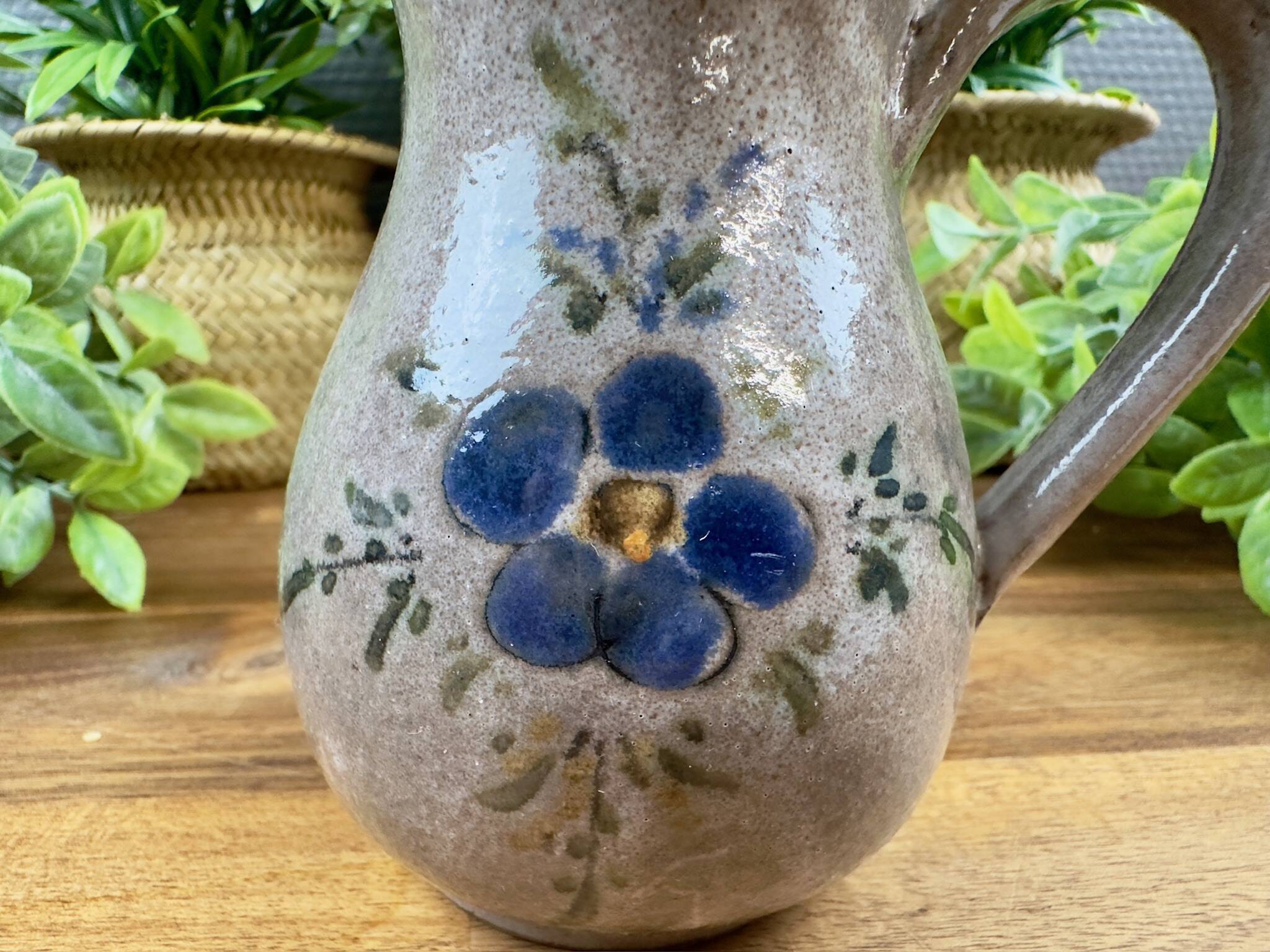 Vintage grey ceramic pitcher with hand-painted blue flower decoration.
