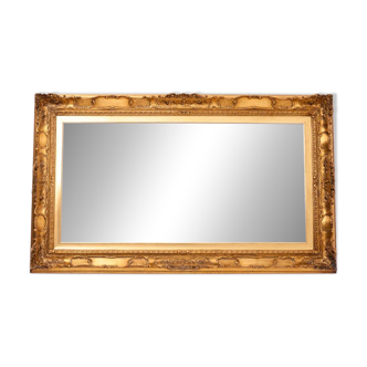 A mirror with a golden, richly carved frame.