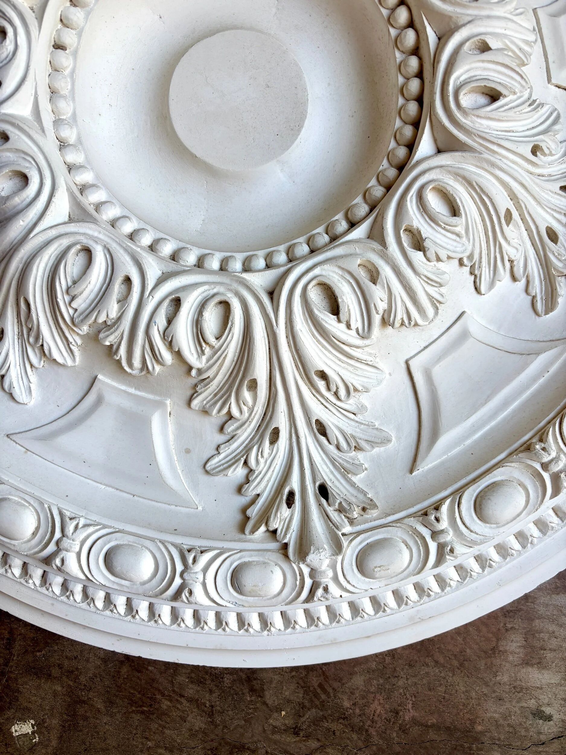 Rosette on white background, decorated with scrolls and beaded frieze ⌀ 61 cm
