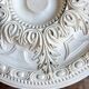 Rosette on white background, decorated with scrolls and beaded frieze ⌀ 61 cm