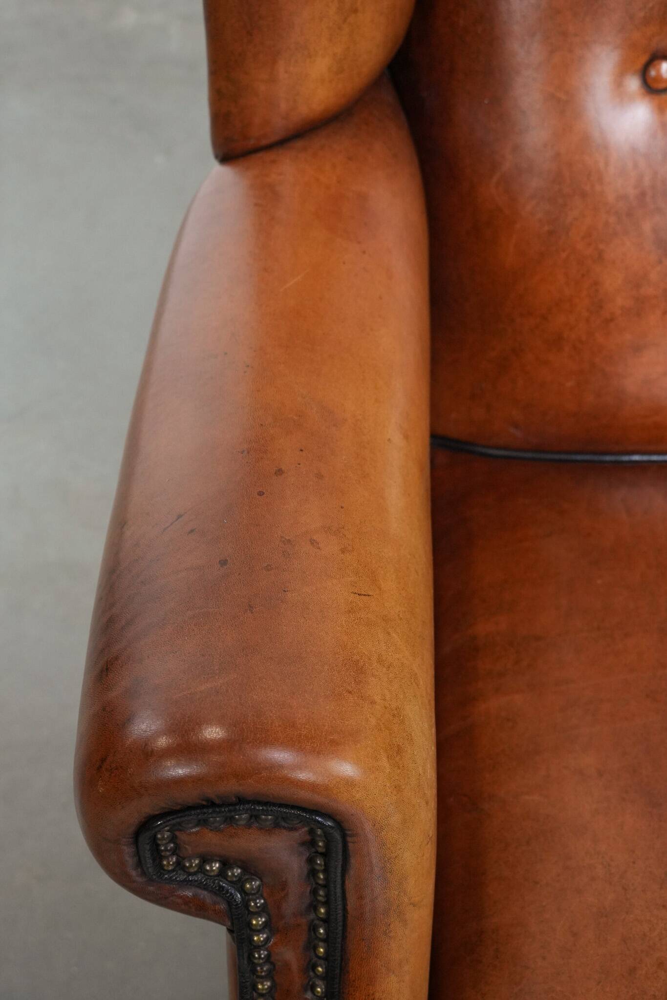 Large sheepskin wingback chair with black piping and decorative nails