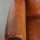 Large sheepskin wingback chair with black piping and decorative nails