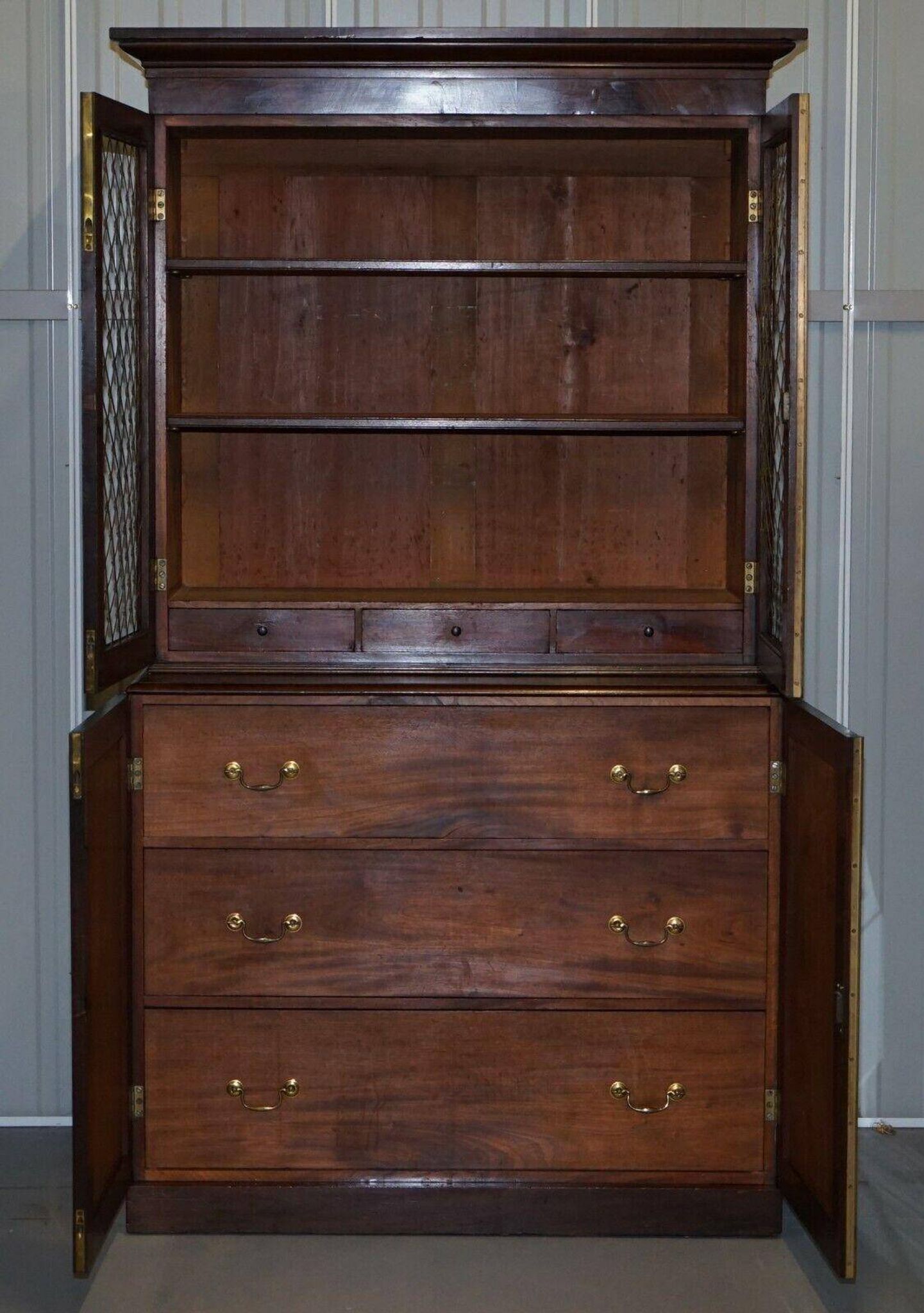 19th-century hardwood library with bronze metal doors and a chest of drawers.