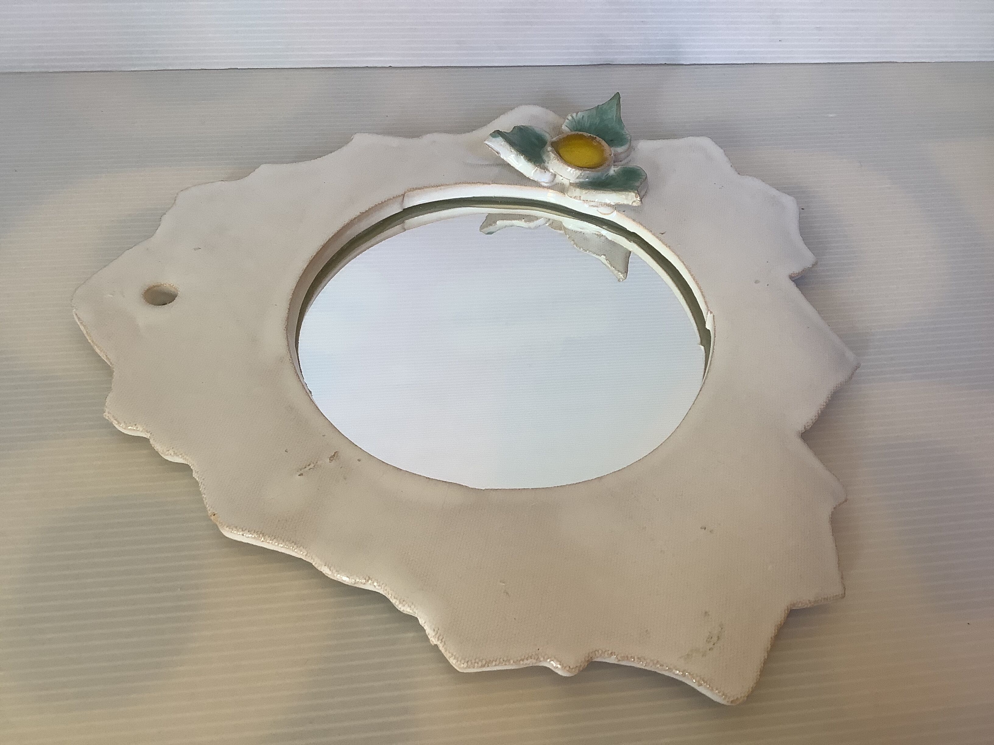 Ceramic mirror with serrated edge and a flower