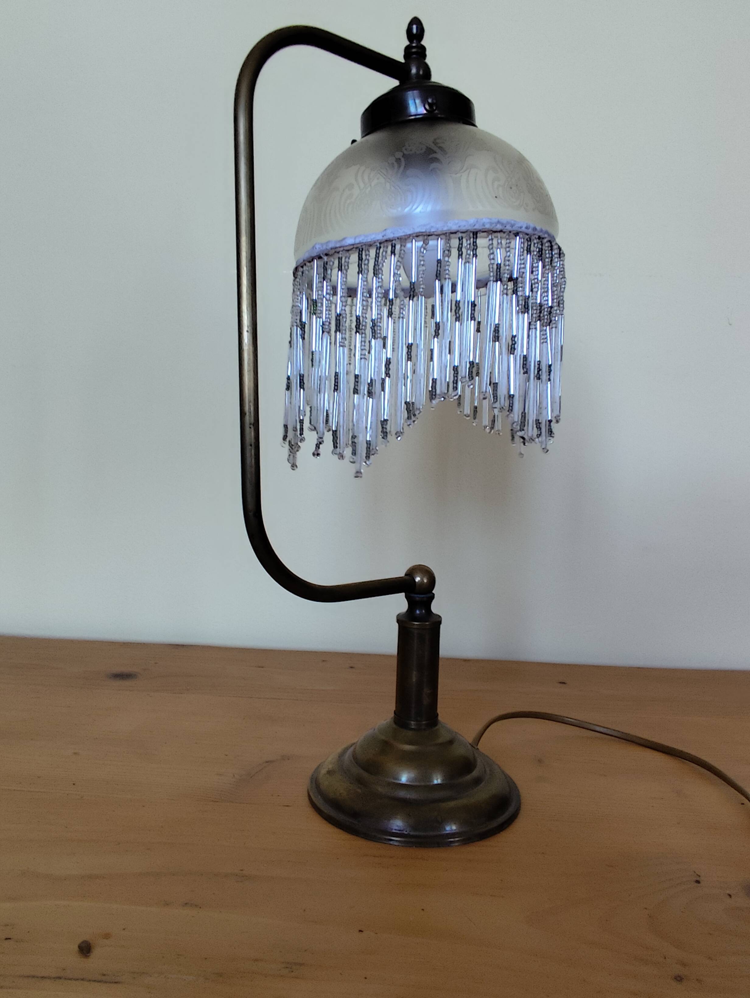 Retro brass lamp with a glass shade and bead fringes.