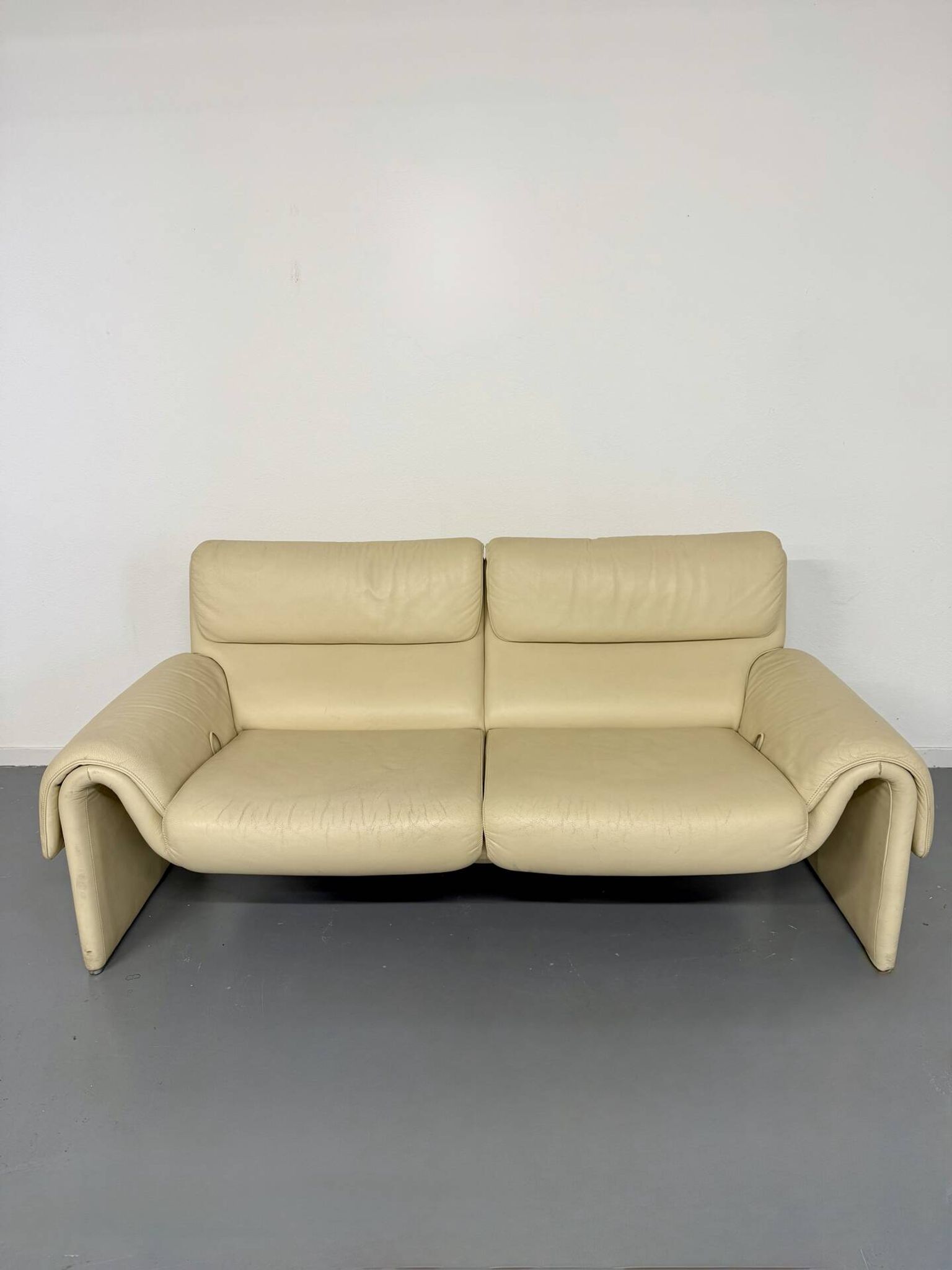 Two-seater designer sofa De Sede DS-2011 in cream leather with adjustable backrest.