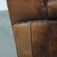 Sheepskin wingback armchair with decorative nails and black piping
