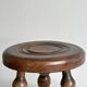 Small three-legged stool made of turned wood.