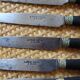 A set of 8 knives with black wooden handles and bolsters.