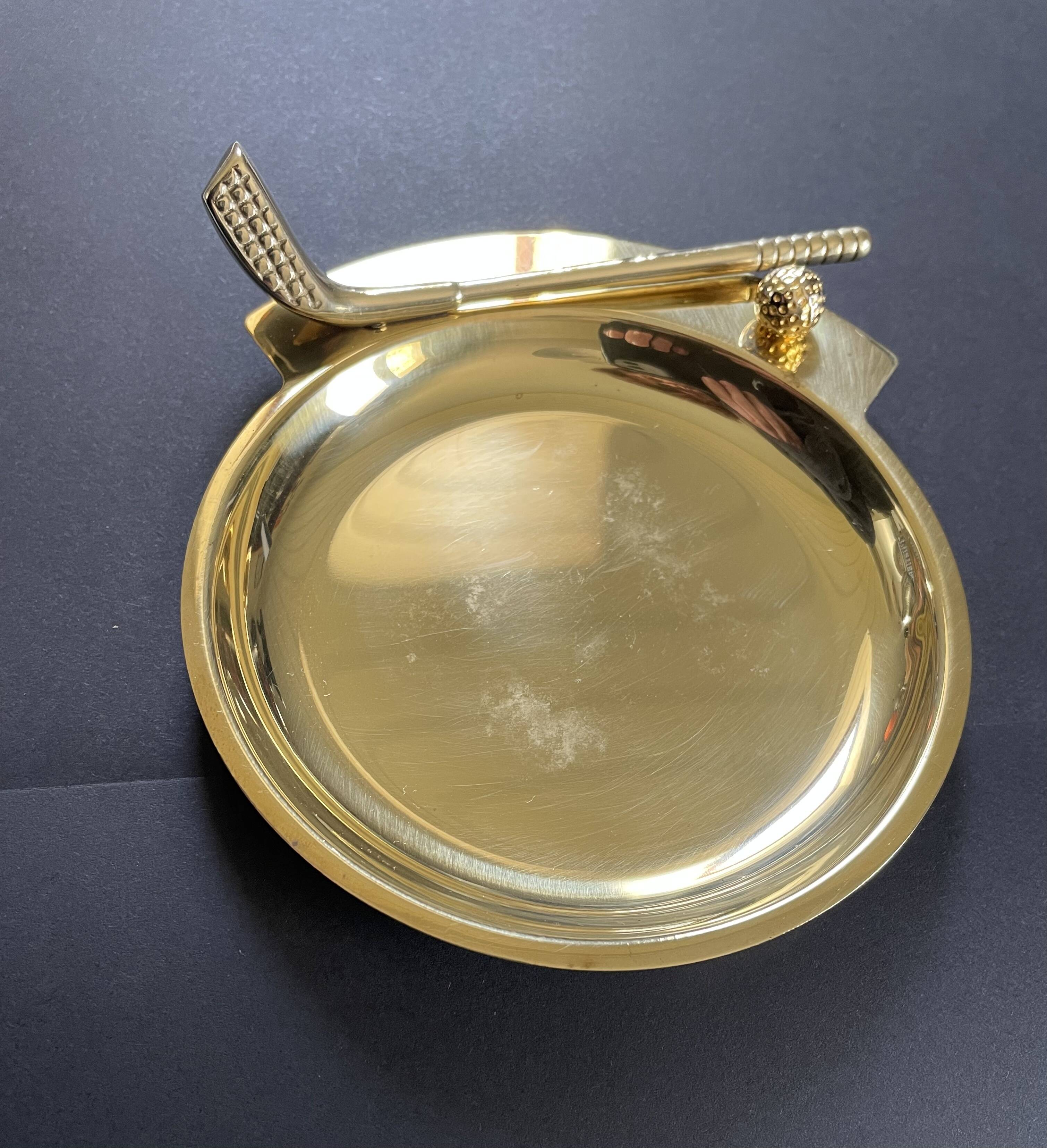 Round brass pocket tray with club and golf ball decoration.