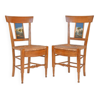 Pair of chairs with slatted backs and painted bands depicting animated landscapes.