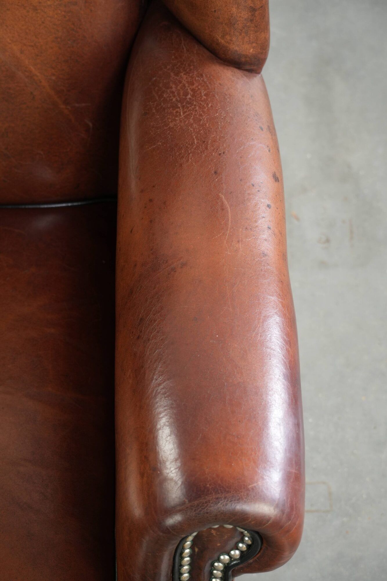 Sheepskin wingback armchair in a warm cognac colour with refined nailhead trim
