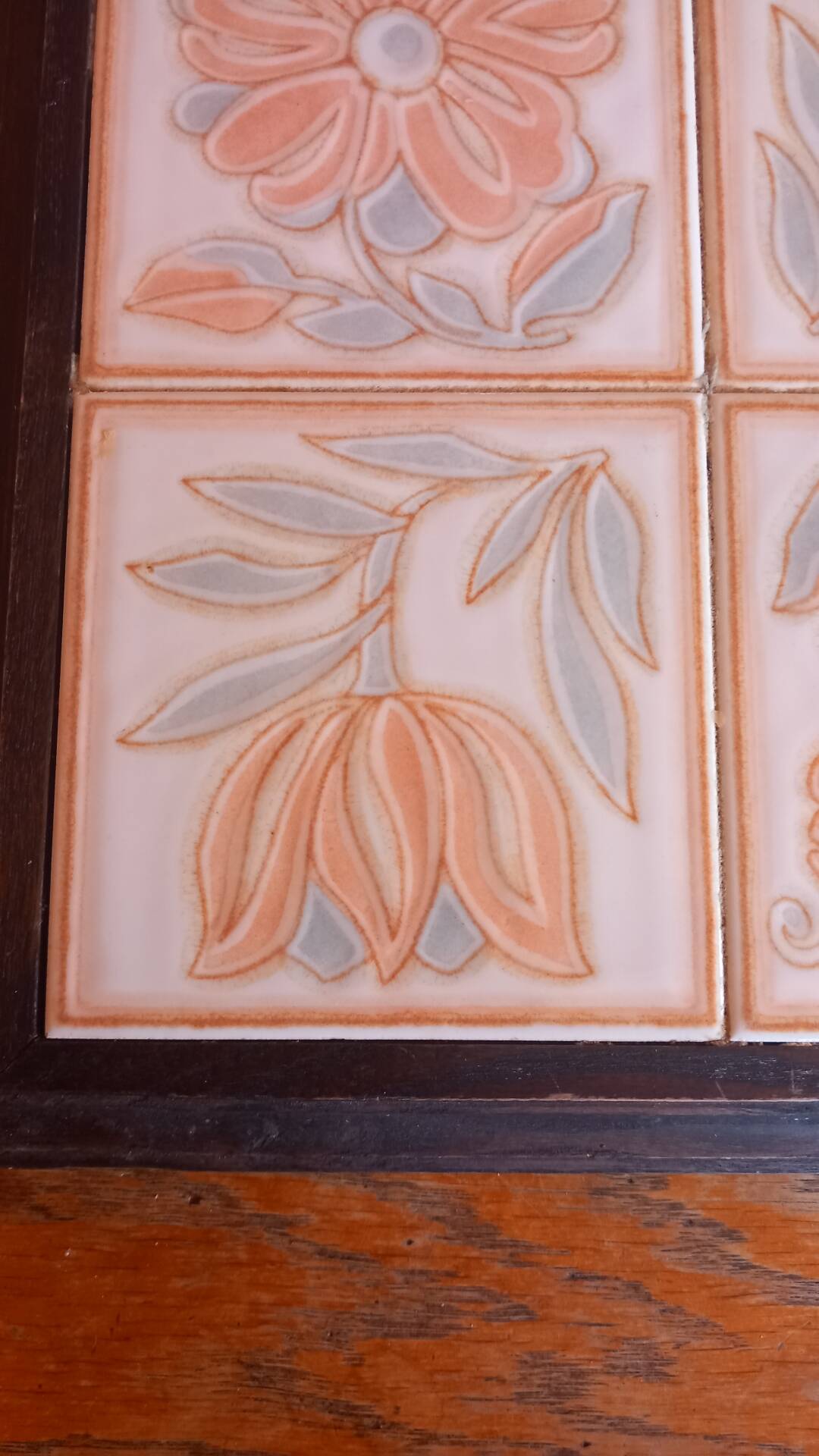 Ceramic tile trivet with floral patterns in pastel tones.