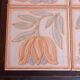 Ceramic tile trivet with floral patterns in pastel tones.