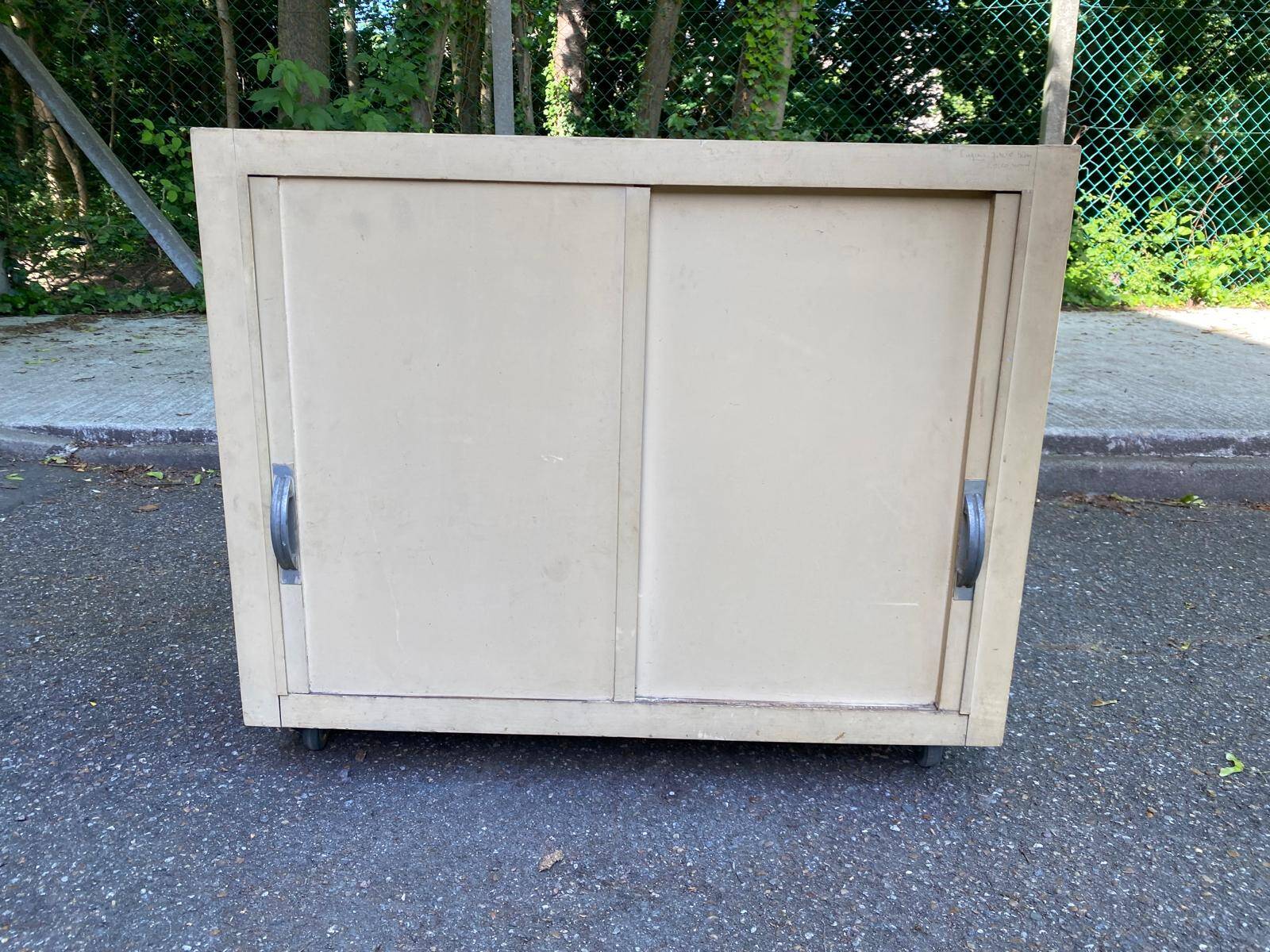 Beige wooden storage cabinet on wheels in industrial style.