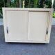 Beige wooden storage cabinet on wheels in industrial style.