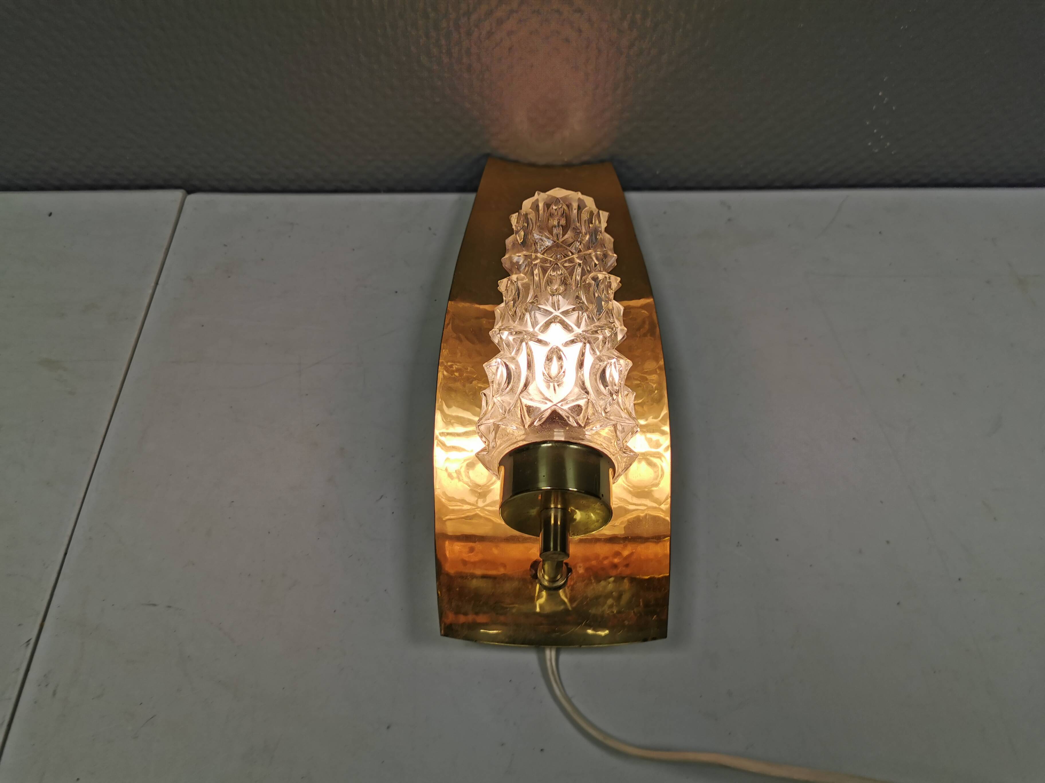 Older wall lamp in brass with hard pressed glass shade.