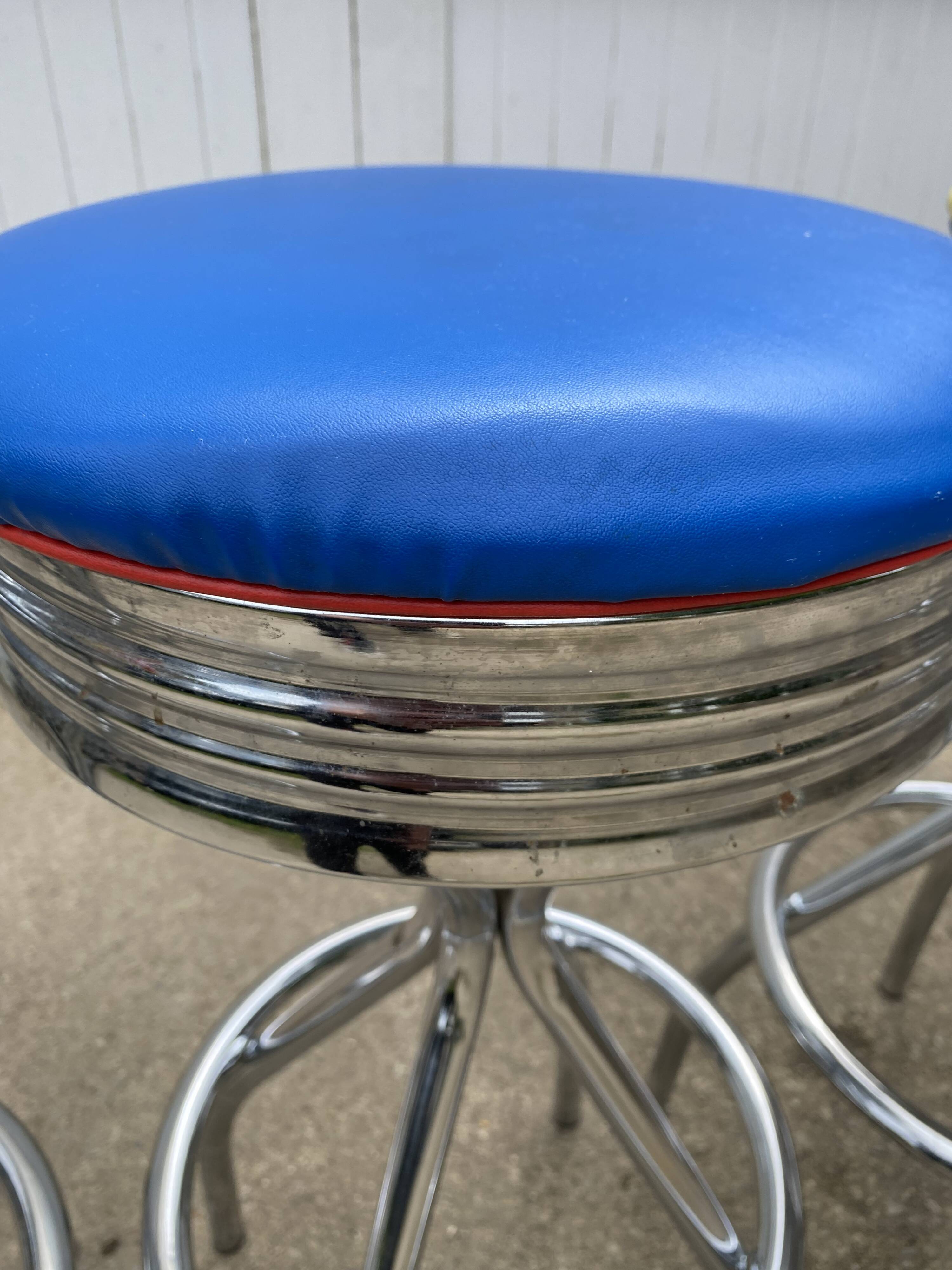 Set of 5 vintage swivel bar stools in blue, red, orange, and yellow.