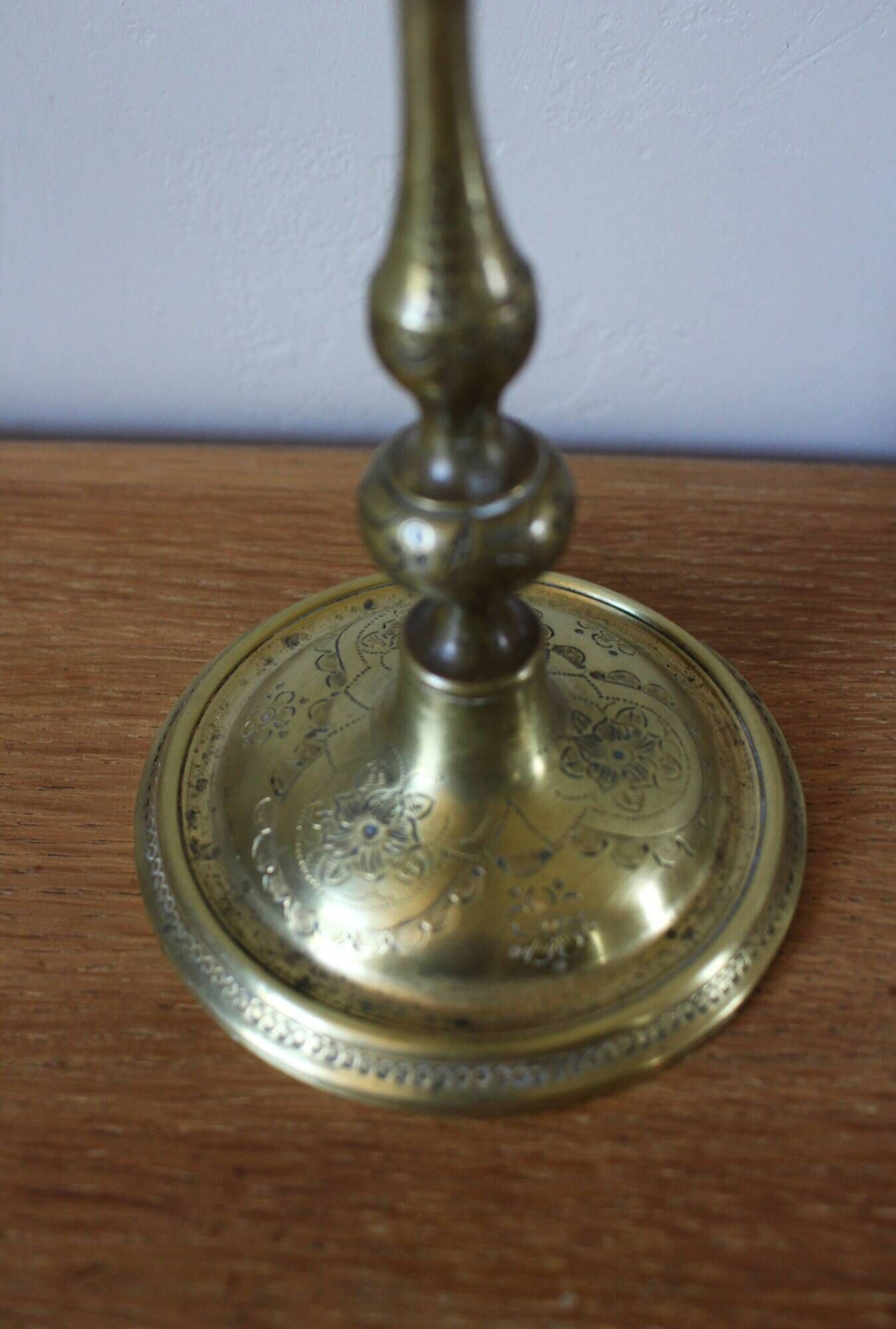 Brass candle holder with flowers and round shape.