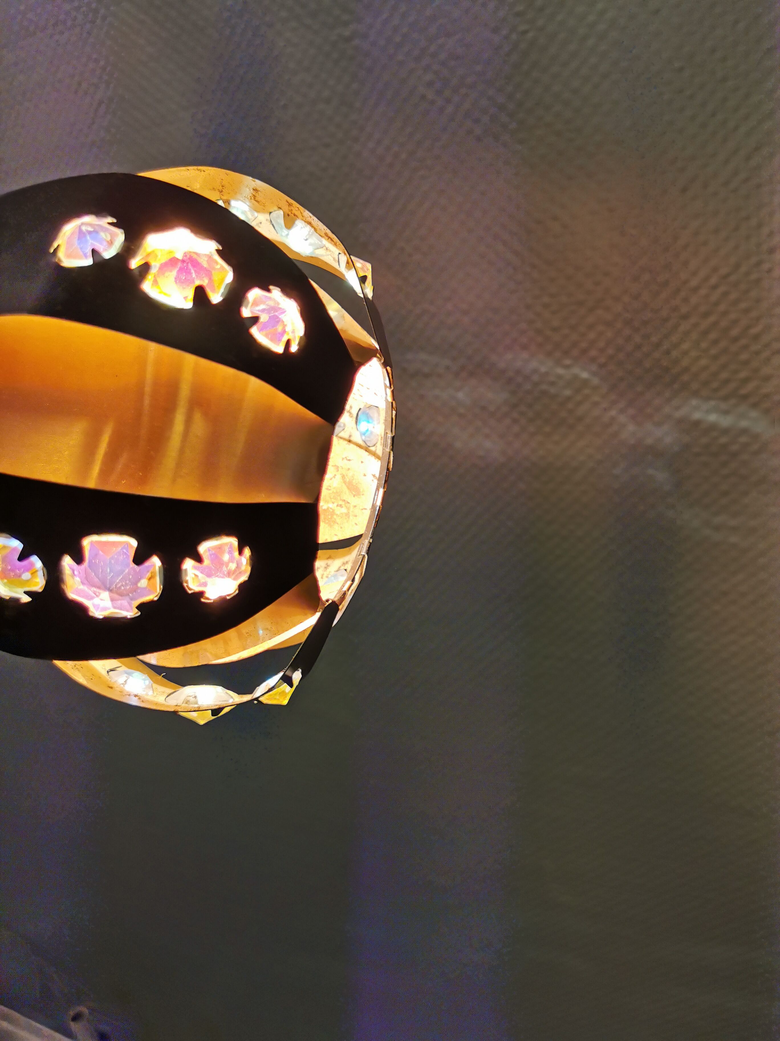 Hanging lamp in thin metal pieces, copper colored and black with prisms.