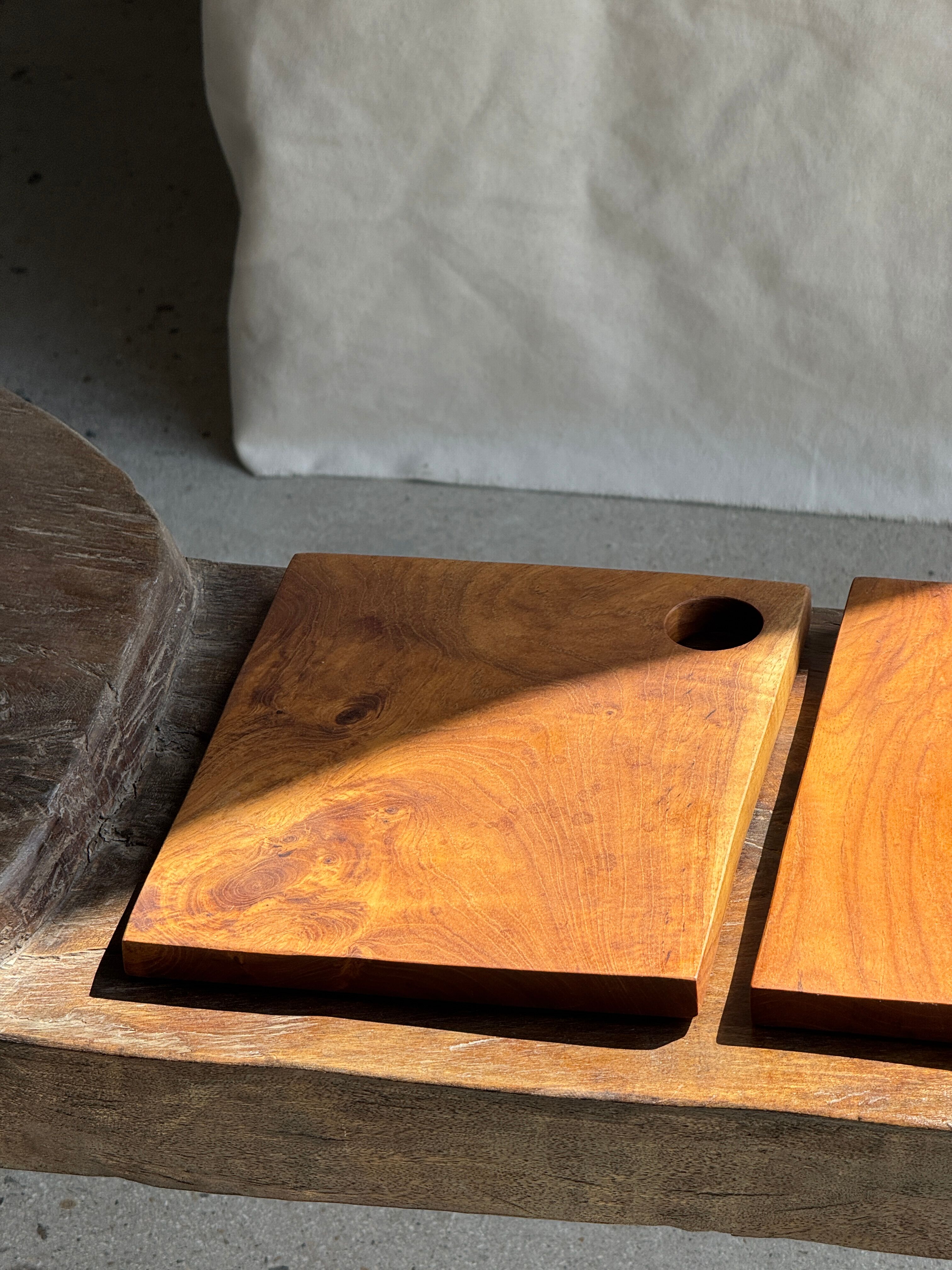 Small rectangular teak monoxyle cutting board with a circular handle.