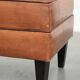 Handy sheepskin ottoman with warm colours finished with black piping