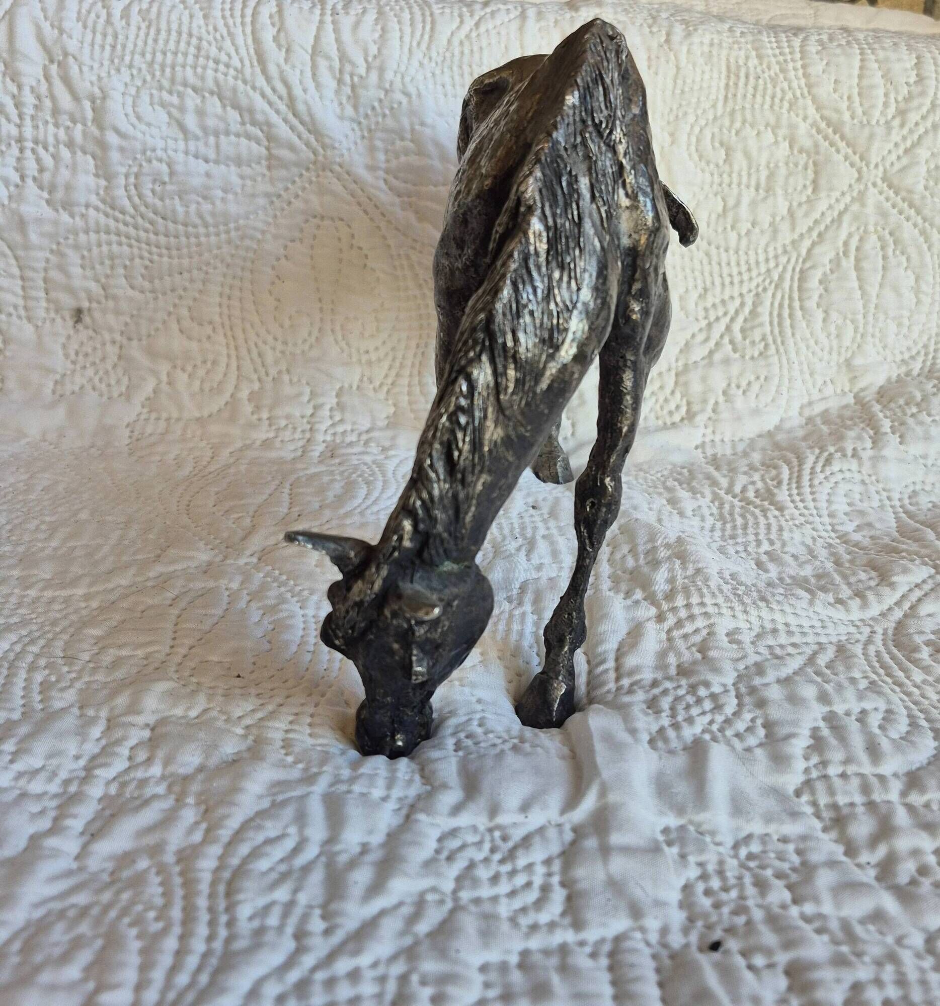 Sculpture of a grazing horse with a silver finish.