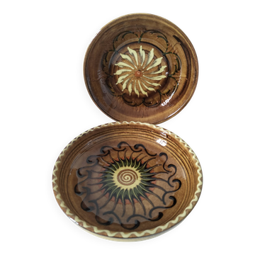 A pair of glazed earthenware deep plates with a solar design.
