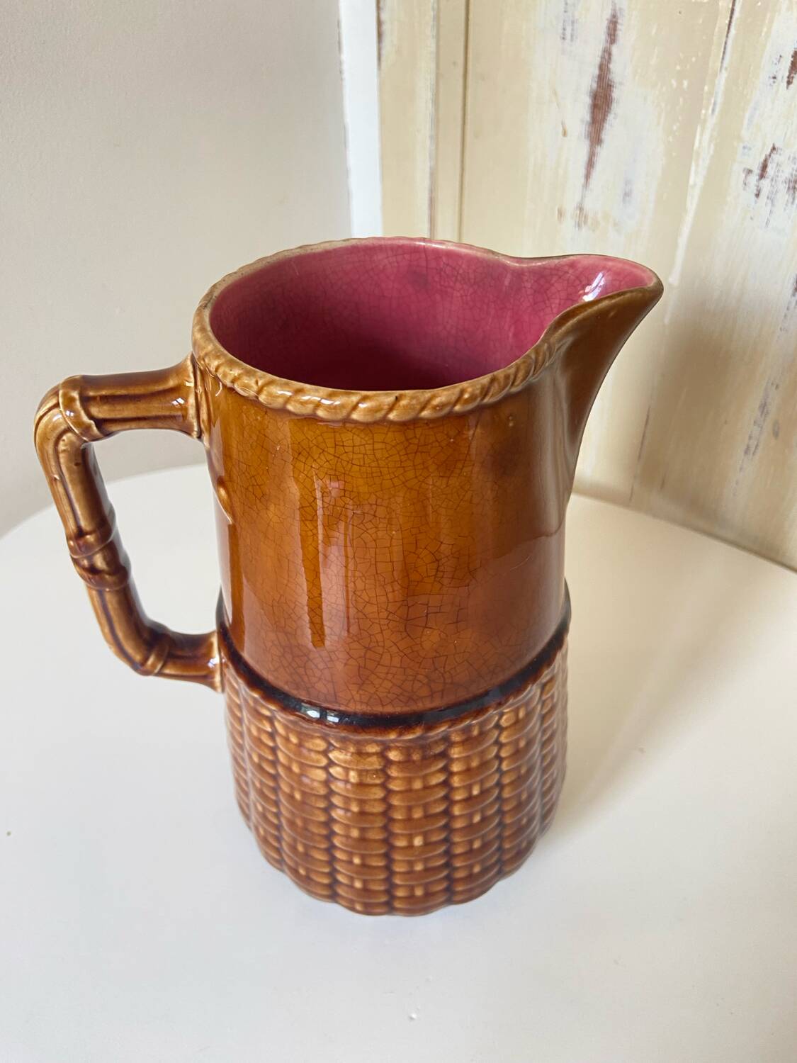 Antique vintage ceramic pitcher or jug from Sarreguemines, France. Brown with a pink interior, imitation basket.