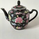 Vintage Chinese teapot with floral polychrome decoration on a black background.