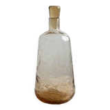 Translucent pinkish iridescent cracked glass bottle.