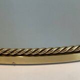 Oval brass mirror surrounded by a cord.