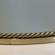 Oval brass mirror surrounded by a cord.