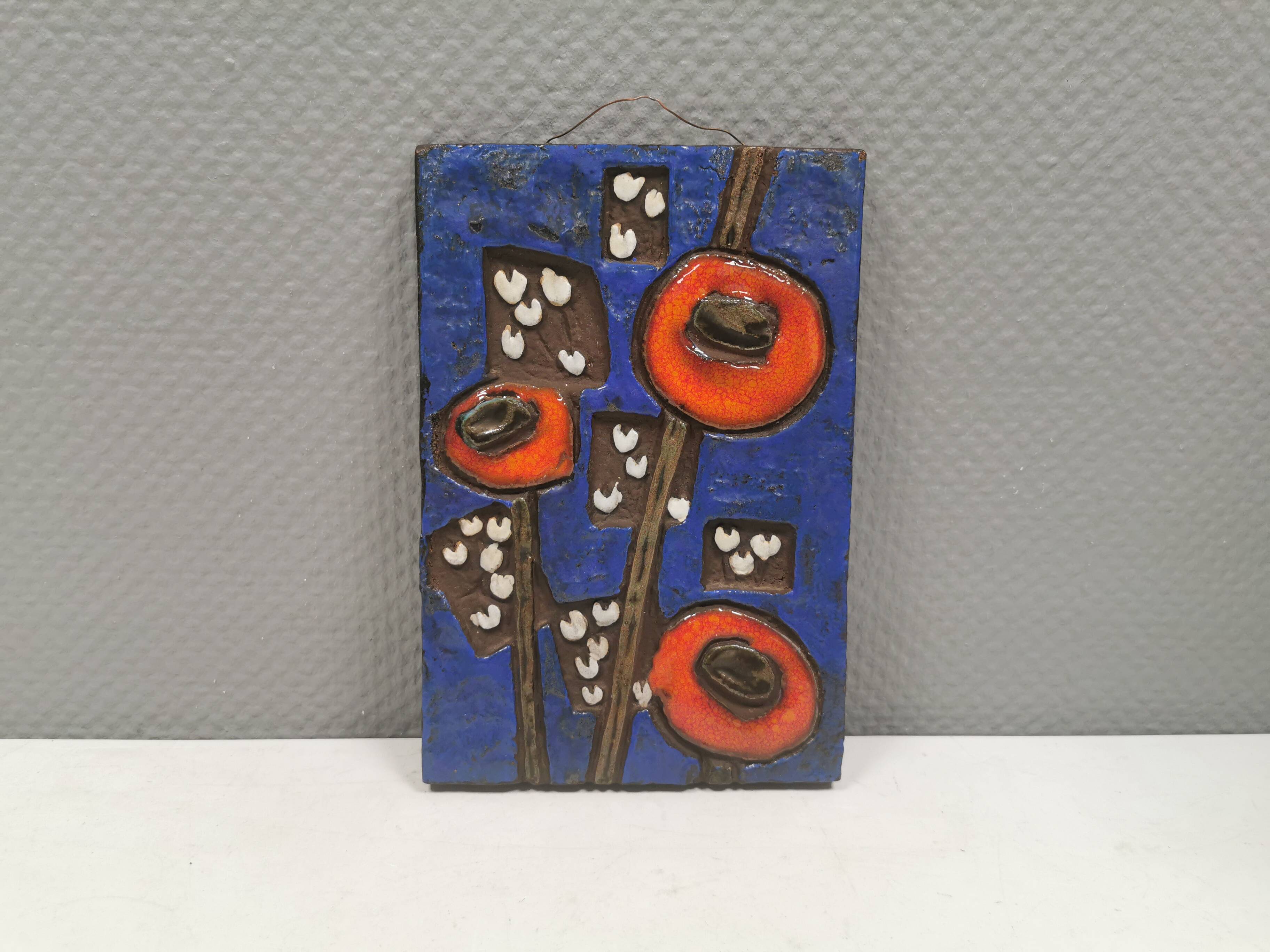 Ceramic relief in attractive blue with a motif of white/red flowers.
