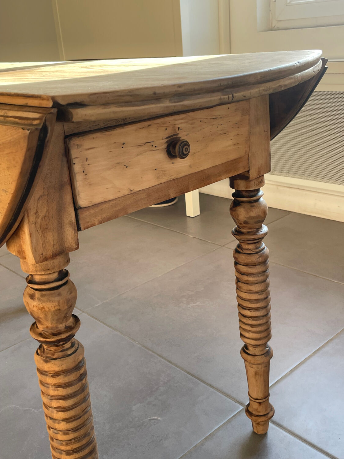 Oval wooden table with drop-leaf edges.