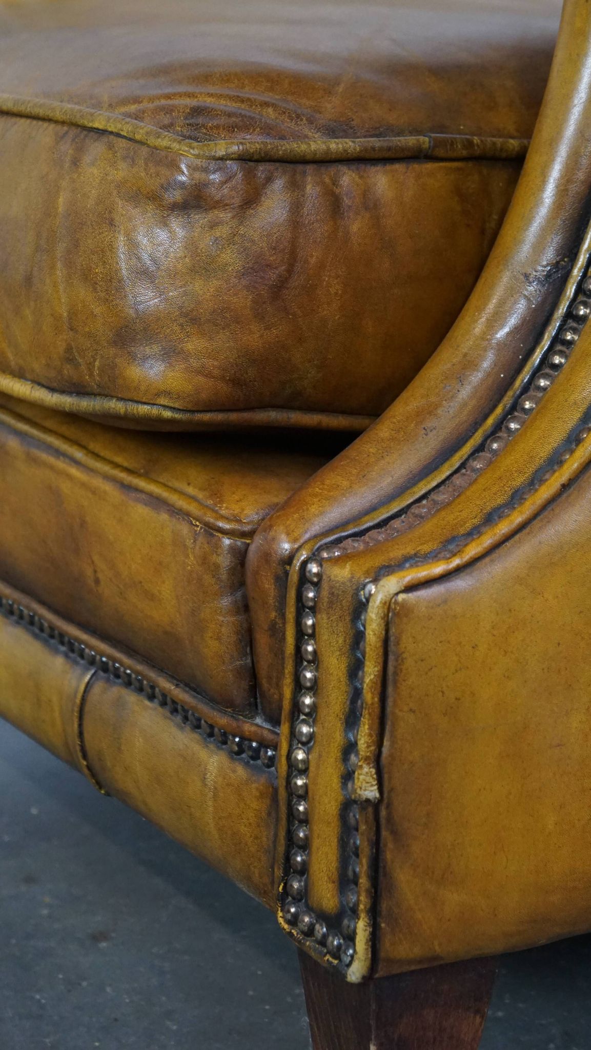 Comfortable large yellow English-style leather armchair with a fine finish and decorative nails