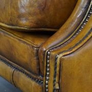 Comfortable large yellow English-style leather armchair with a fine finish and decorative nails