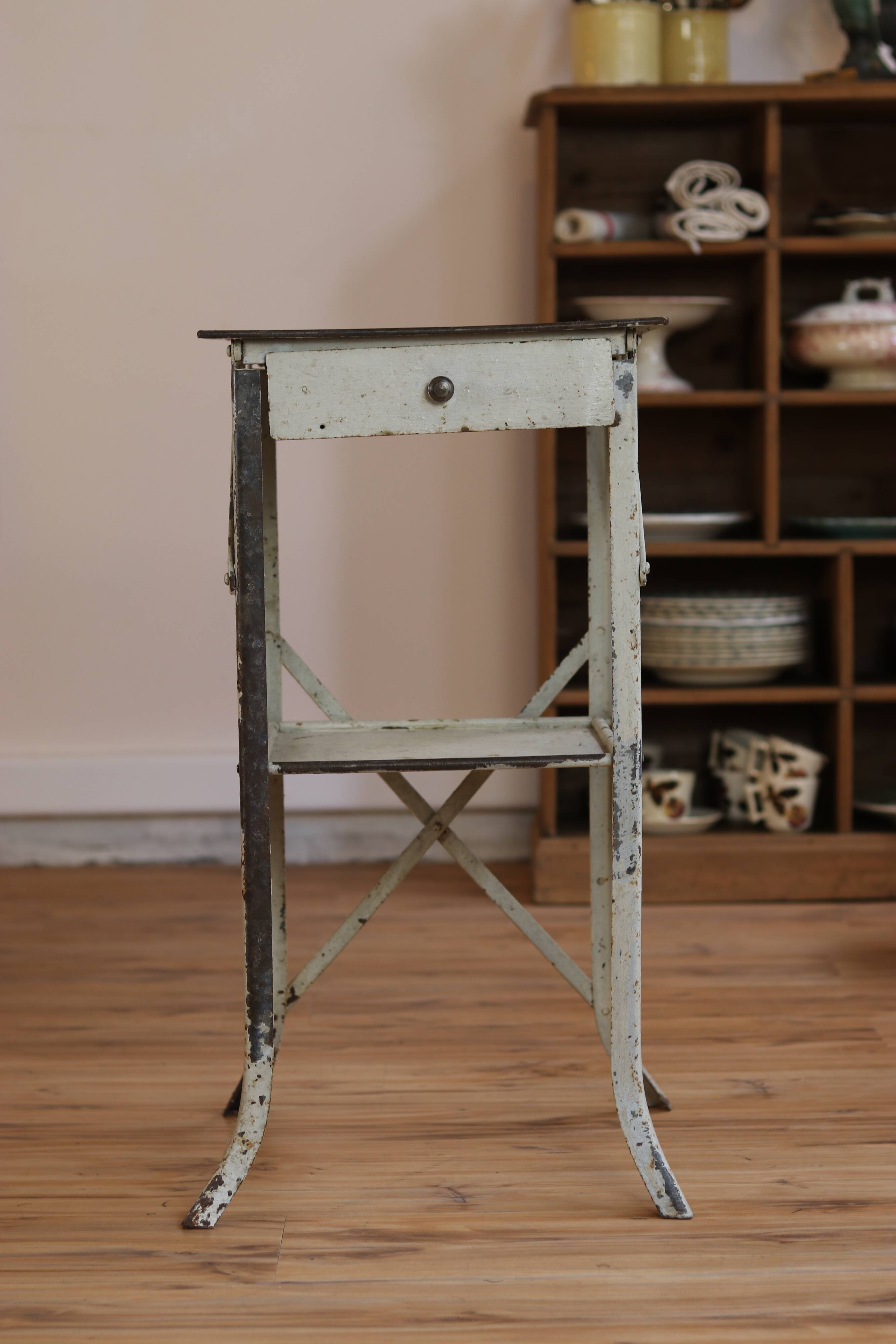 Painted metal side table, patinated white, with a drawer and two shelves