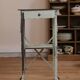 Painted metal side table, patinated white, with a drawer and two shelves