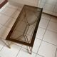 Rectangular neoclassical coffee table in gilded brass with a glass top.